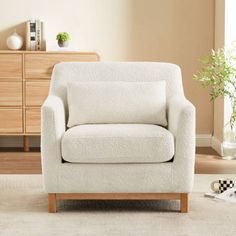 a white chair sitting on top of a rug in a living room next to a dresser