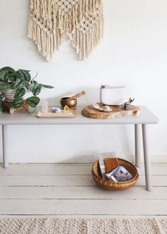 a white table topped with plates and bowls next to a potted plant on top of a wooden floor