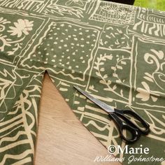 a pair of scissors sitting on top of a table next to a piece of cloth