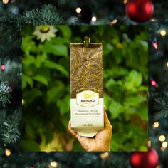 a person holding up a box of coffee in front of a christmas tree