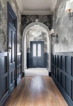 an entry hall with black doors and wood floors