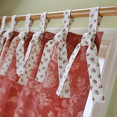 red and white curtains hanging from a wooden rod