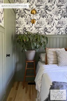 a bed sitting in a bedroom next to a green wall with flowers and plants on it