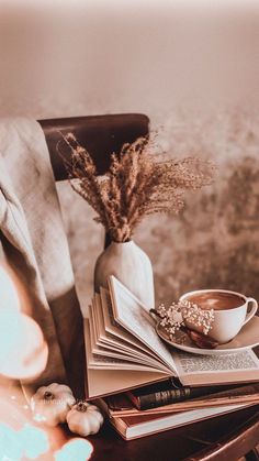 a stack of books sitting on top of a table next to a vase filled with flowers