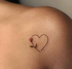 a small tattoo on the back of a woman's shoulder with a heart and flower