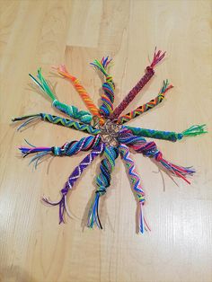 a group of multicolored string art pieces on a wooden surface