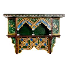 an elaborately painted wooden cabinet with green and blue designs on the front, against a white background