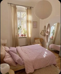 there is a bed with pink sheets and pillows in the room next to two windows