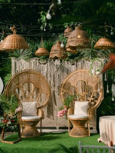 two wicker chairs sitting next to each other on top of a lush green field