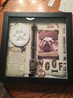 a dog's paw prints are displayed in a shadow box on a wooden table