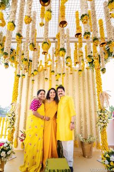 two women standing next to each other in front of a yellow and white floral arrangement