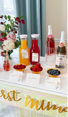 a table topped with fruit and drinks on top of a white tablecloth covered table