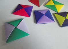 four different colored origami pieces sitting on top of a white table next to each other