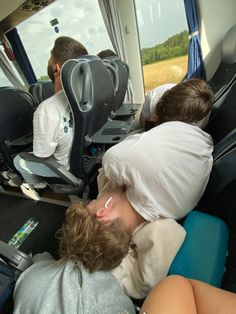 two people sleeping on seats in the back of a bus, with one person covering his face