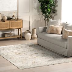 a living room with a gray couch and white rug on the floor in front of a mirror