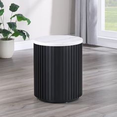 a black and white round side table with a plant in the corner next to it