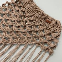 two crocheted shawls with fringes on top of each other, one in beige and the other in brown