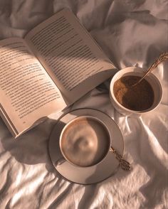 an open book and cup of coffee on a bed