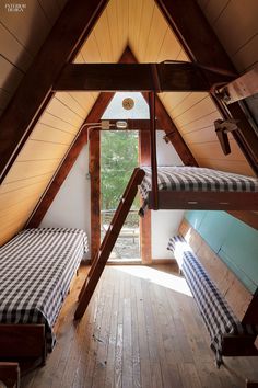 there are two beds in the attic with checkered sheets on them and one bed is made up