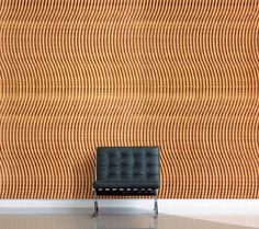 a black chair sitting in front of a wall with an orange pattern on the wall