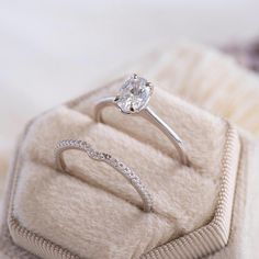 a diamond engagement ring sitting on top of a white velvet cushion in a jewelry box