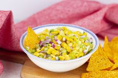 a bowl filled with corn salsa next to tortilla chips