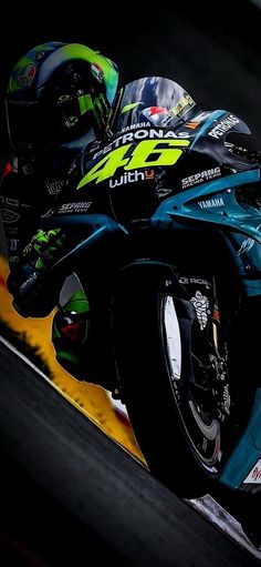 a man riding on the back of a blue motorcycle down a race track next to a yellow line