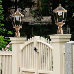 two lamps on top of a white fence