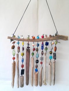 a wind chime hanging from a wooden branch with beads and wood sticks attached to it