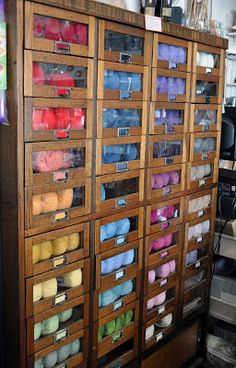 a large wooden cabinet filled with lots of different colored spools of thread and yarn