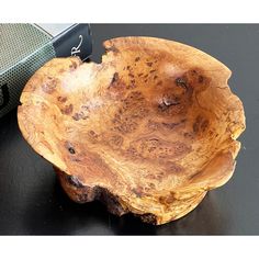 a wooden bowl sitting on top of a black table next to a green speaker box