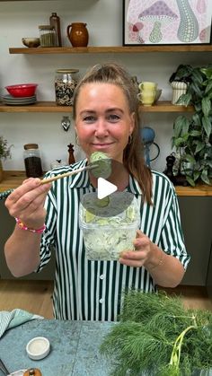 a woman is holding a spoon in her hand and mixing something into a glass bowl