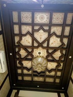 an ornate ceiling in the middle of a room with white and brown tiles on it