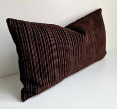 a brown corded pillow sitting on top of a white table next to a wall