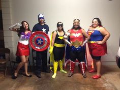 four people dressed up as superheros posing for a photo in front of a white wall