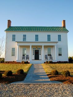 a large white house sitting on top of a lush green field