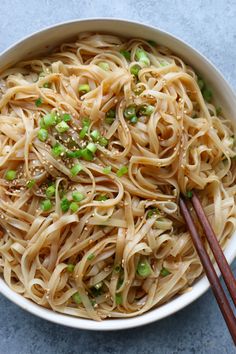 a white bowl filled with noodles and green onions