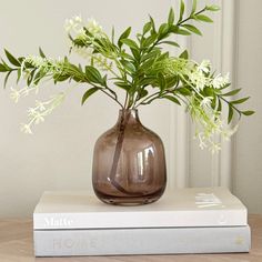 a brown vase with white flowers sitting on top of a book