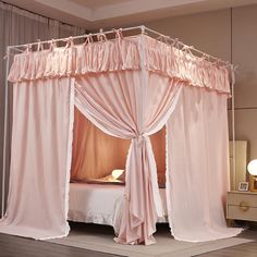 a canopy bed with pink drapes and curtains on it's sides in a bedroom