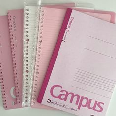 three pink notebooks with writing on them are lined up next to each other,