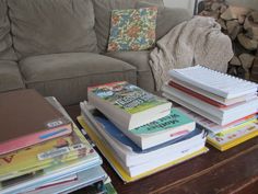 a stack of books sitting on top of a wooden table next to a couch in a living room