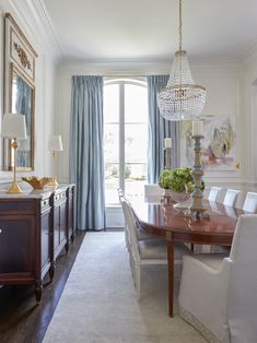 a dining room table with white chairs and a chandelier hanging from the ceiling