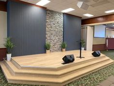 an empty conference room with two speakers on the stage and three planters in front of it