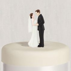 a wedding cake topper with a bride and groom standing next to each other in front of a white background