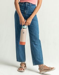 a woman in pink shirt and jeans holding a water bottle