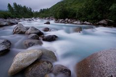 a river with rocks in it and trees around