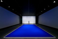 an empty room with a blue carpet and white walls, in front of a large screen