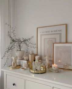 a white dresser topped with vases and candles next to a framed photograph on top of it