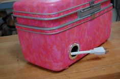 a pink suitcase with a white toothbrush in it on a wooden table next to a pair of scissors