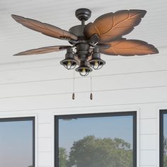 a ceiling fan with three light bulbs hanging from it's center point in front of two windows